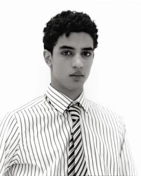 Portrait of a young man wearing a striped button-down shirt and tie against a white background
