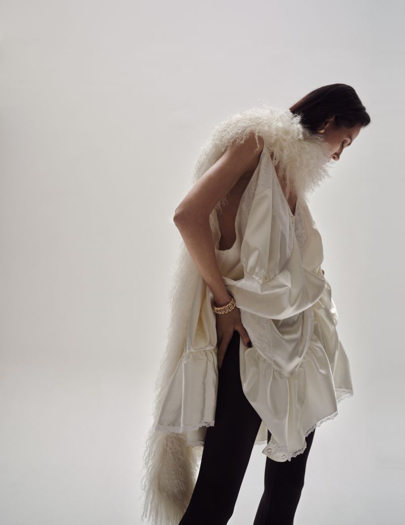 Model Aymeline Valade wearing a white ruffled top and feathered scarf against a light grey background for Tiffany & Co.