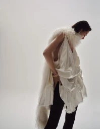 Model Aymeline Valade wearing a white ruffled top and feathered scarf against a light grey background for Tiffany & Co.