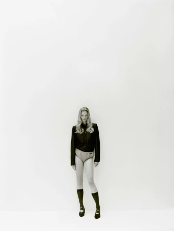 Model standing against a plain white background wearing a dark jacket, light shorts, knee socks, and flat shoes.