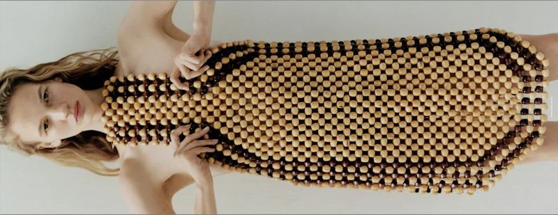 Model wearing a structured wooden bead dress against a plain white studio backdrop for the Double Dutch project.
