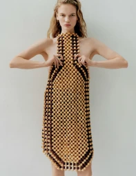 Model wearing a structured wooden beaded dress against a neutral grey studio background for the Double Dutch project.