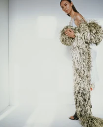 Model Quannah ChasingHorse in a textured feathered garment posing against a white seamless background