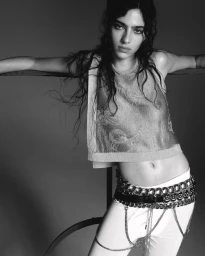 Model Loli Bahia wearing a metallic sheer top and white trousers with chain belts in a black and white editorial shoot by Oliver Hadlee Pearch for Pop Magazine