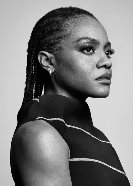 Black and white portrait of an adult female looking off-camera, featuring her braided hair and simple stud earring, against a neutral backdrop.