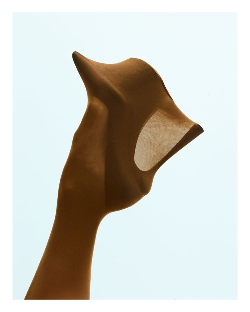 Brown pantyhose are elegantly displayed against a light blue background in a studio shot showcasing the garment's texture and form.
