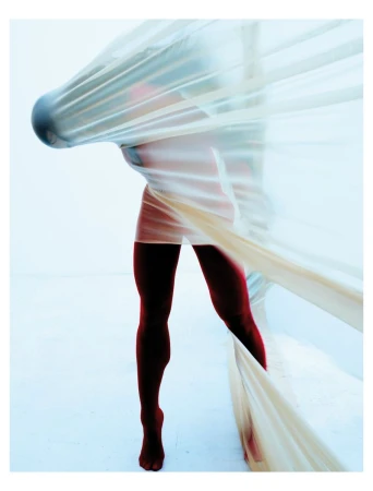 Abstract studio shot of a person with lower body visible, draped in translucent fabric, creating an ethereal and artistic effect.