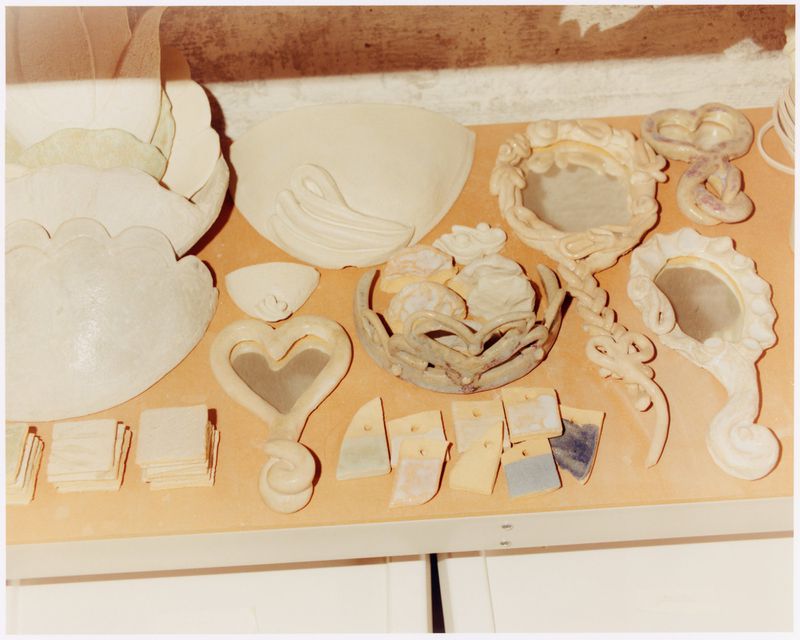 Still life of unpainted ceramic bowls, vessels, and decorative objects arranged on a counter, showcasing craft and artistic creation.