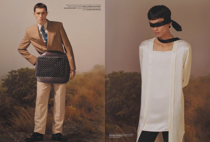 Editorial shot of two male models in contrasting outfits. One wears a tan suit, and the other a white button up with a blindfold.