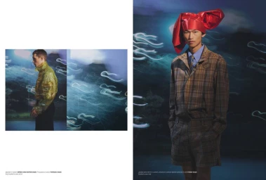 Model wearing a plaid jacket and shorts with a red sculptural headpiece against a dark surreal background