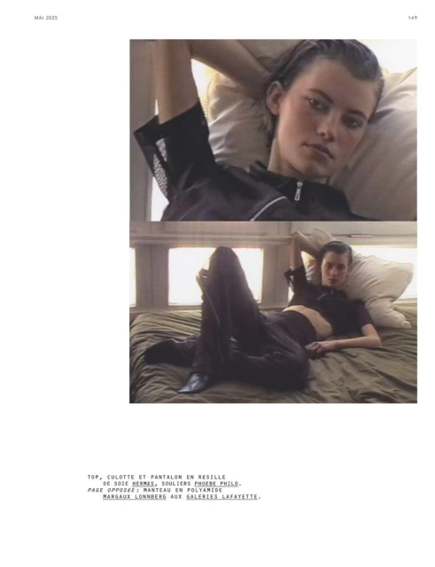 Editorial fashion shot featuring a young woman in black loungewear reclining on a bed, styled for a minimalist aesthetic.