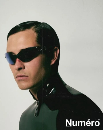 Close-up portrait of Francisco Lachowski wearing dark futuristic sunglasses and a black high-collar garment against a plain light background