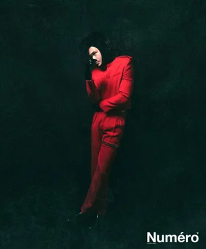 Francisco Lachowski wearing a red suit and dark gloves against a dark textured background for Numero Homme Netherlands.