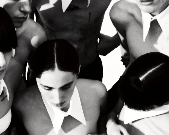 Group of young adults wearing white collars, set against a bright backdrop in a black and white studio-style photograph.