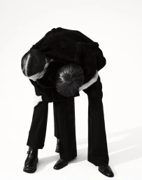 Two models posing intertwined wearing black clothing against a white seamless background for Boycott Magazine