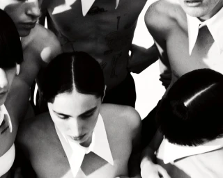 High-angle monochrome portrait of a group of models wearing white collars against a bright background.