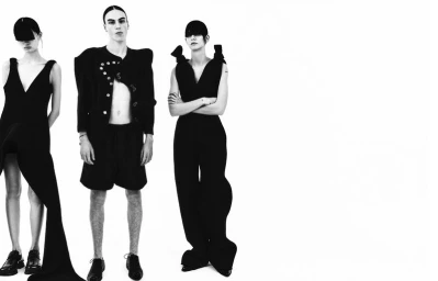 Three models in black avant-garde outfits posing against a clean white seamless studio background for Boycott Magazine