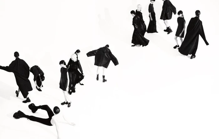 Multiple models in black attire moving diagonally across a clean white studio background in Boycott Magazine editorial