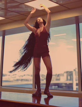 Woman in red outfit with long, dark curly hair poses in front of a large window with a city view, illuminated by overhead lighting.