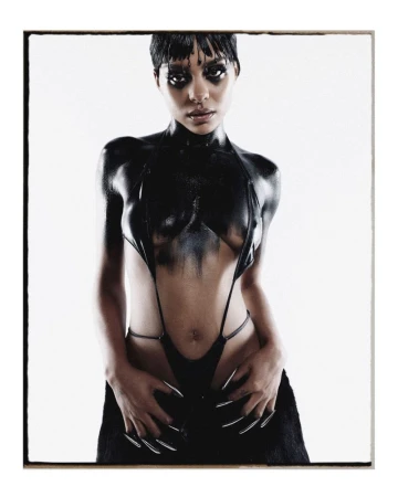 Striking portrait of a model in a glossy black body suit with long nails against a white background in a photo studio setting.