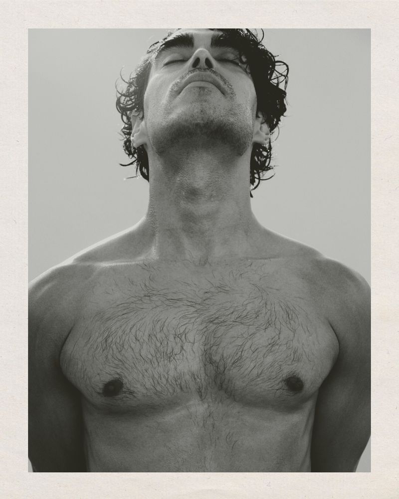 Close-up portrait of a shirtless man with his head tilted back and eyes closed, photographed in monochrome.
