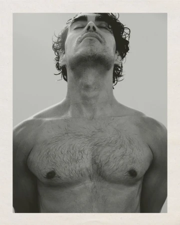Close-up portrait of a shirtless man with his head tilted back and eyes closed, photographed in monochrome.