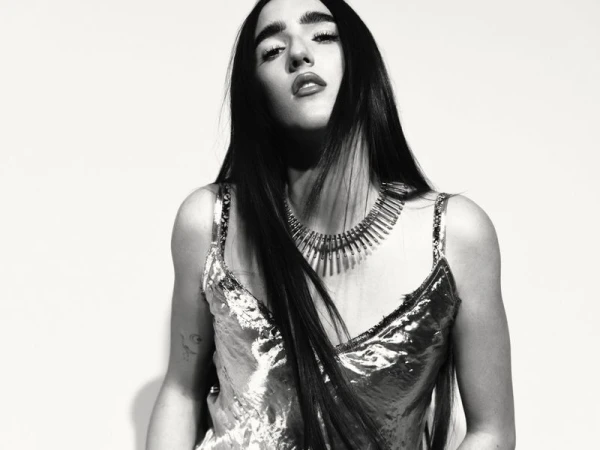 Black and white portrait of a woman wearing a metallic strapless top and statement spike necklace against a white background.