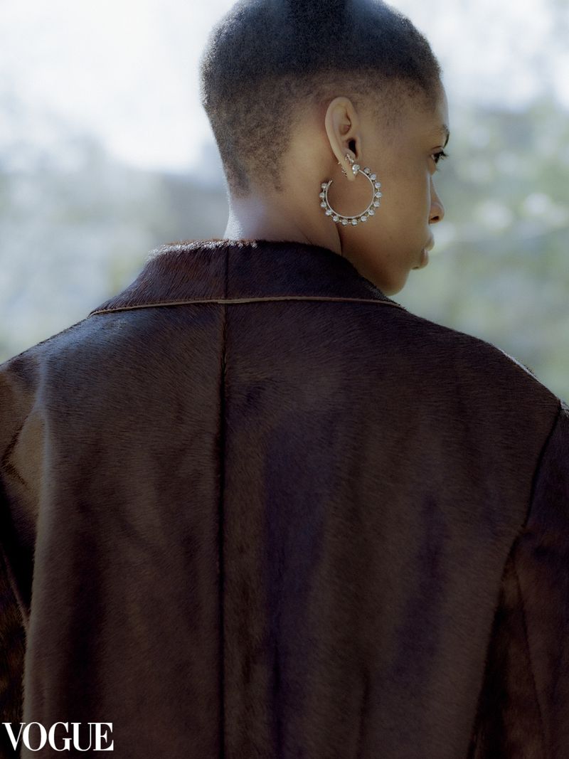 Woman in brown jacket with silver hoop earrings. Close up profile with a blurred background.