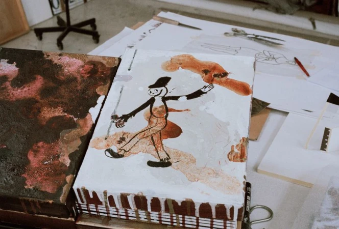 Whimsical character art on display in an artist's studio, featuring a vintage cartoon figure, painted on a block with visible brushstrokes and brown drips.