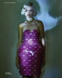 Model with platinum blonde hair wearing a strapless magenta dress and gold necklace against a muted background with light shadows