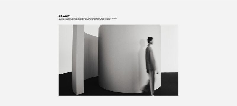 Monochrome fashion shot of a blurry man in a suit walking past cylindrical and rectangular structures, creating a minimalist scene.