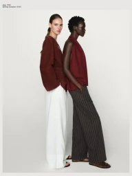Two female models standing side-by-side against a white seamless background wearing burgundy tops and trousers