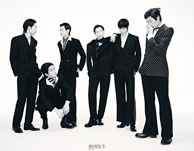 Black and white fashion shot features six Asian male models in stylish black suits against a bright backdrop, showcasing contemporary formal wear.