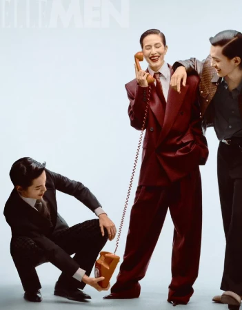 Three asian adult male models in suits pose with a vintage telephone in a studio setting, highlighting retro fashion and communication.