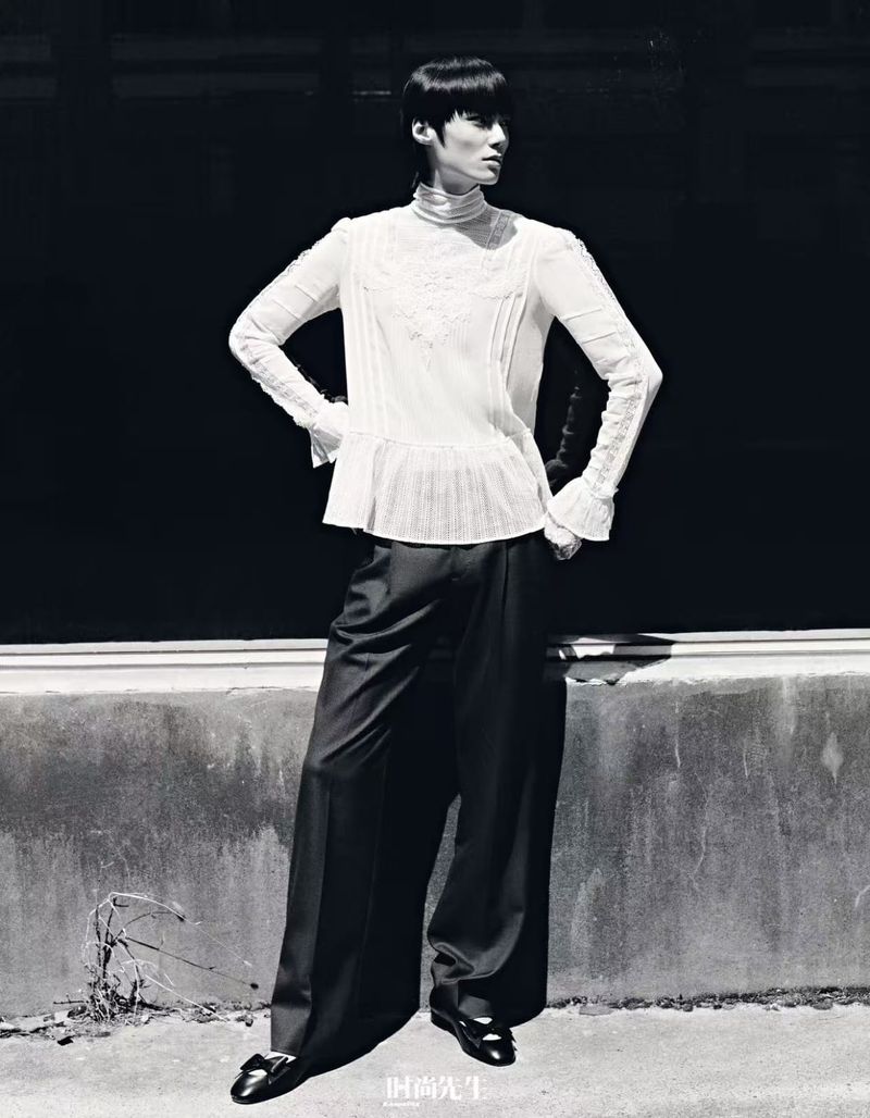 Model in white high-neck blouse and dark trousers posing outdoors for Elle Men China