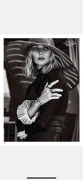 Black and white portrait of a female model wearing a wide-brimmed striped hat and ruffled blouse with rings.