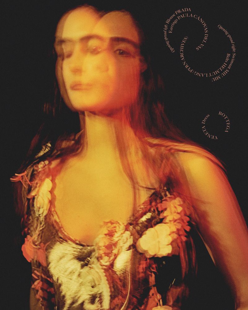 Artistic fashion poster featuring blurred image of woman in floral dress against a dark background, with designer text overlay.