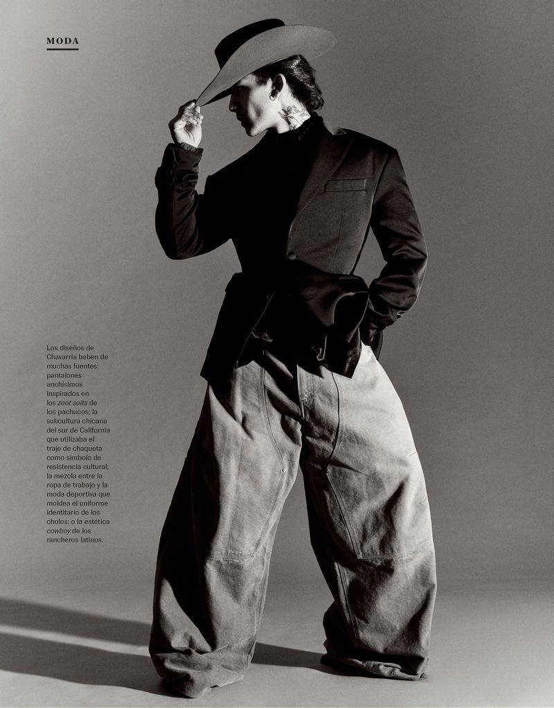 Model Christiano Wennmann wearing a cowboy hat, dark blazer, and wide trousers against a grey seamless background.
