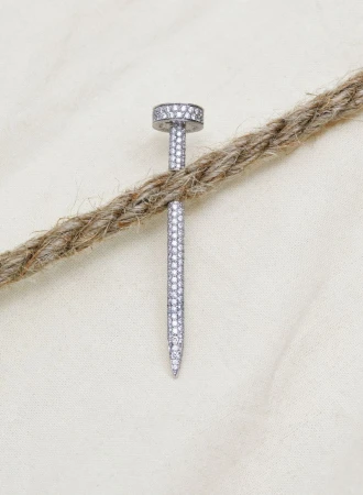Diamond-encrusted nail jewelry made of white gold, set on a light background with a textured rope detail.