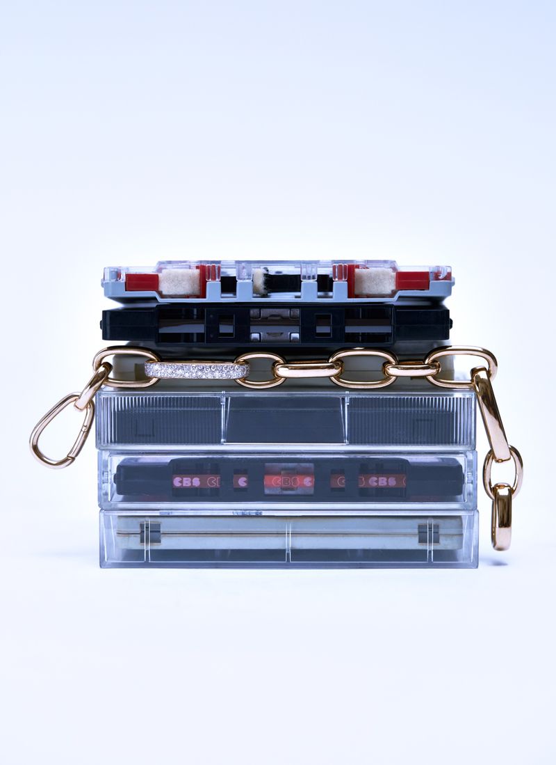 Stack of vintage audio cassette tapes with gold chain and clasps. Retro music accessories on white background.