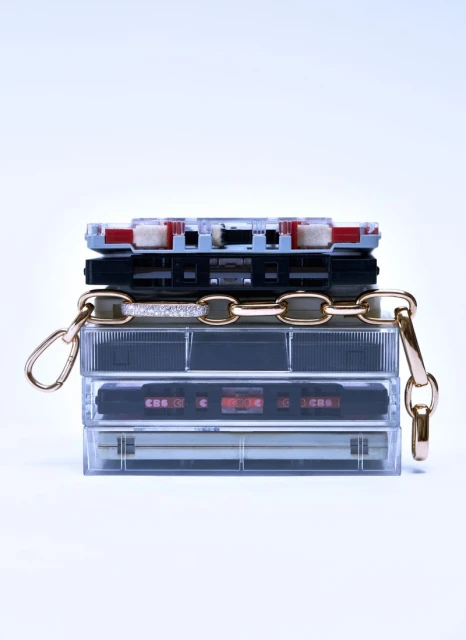 Stack of vintage audio cassette tapes with gold chain and clasps. Retro music accessories on white background.