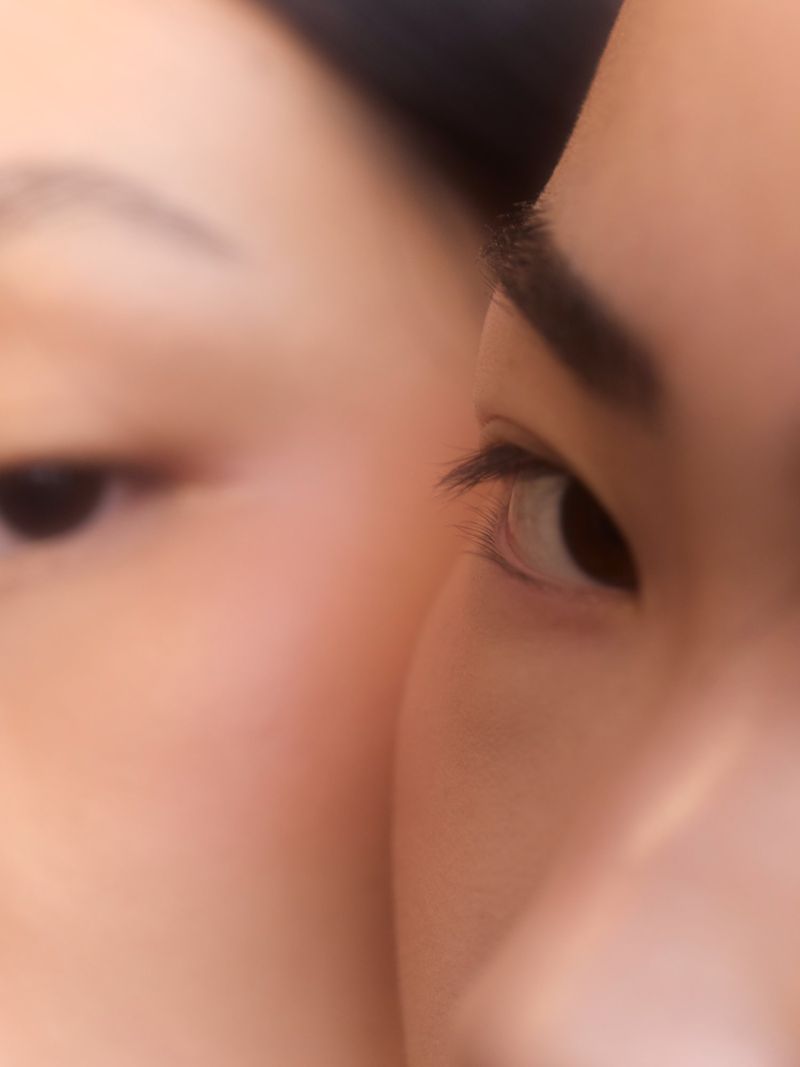 Macro close-up of two adults with skin details, one looking off to the right and the other straight ahead, in shallow focus.