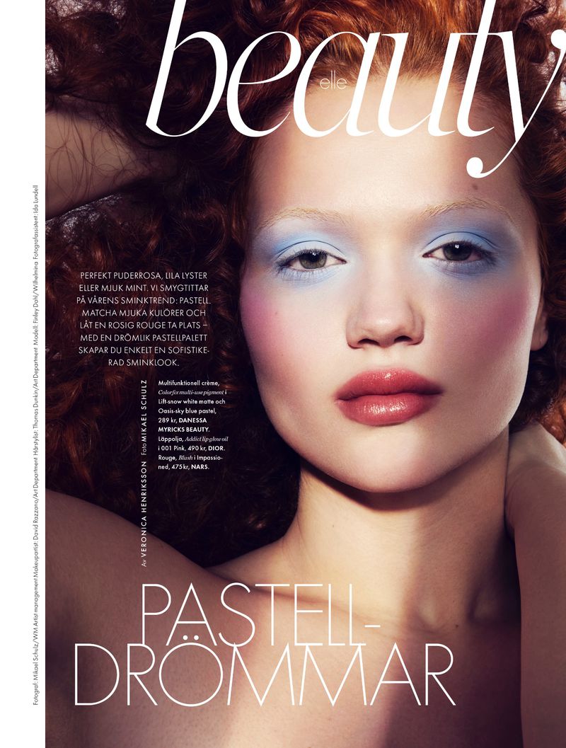 Beauty magazine cover featuring a woman with pastel eye makeup, glossy lips, and curly red hair, showcasing a beauty and fashion theme.