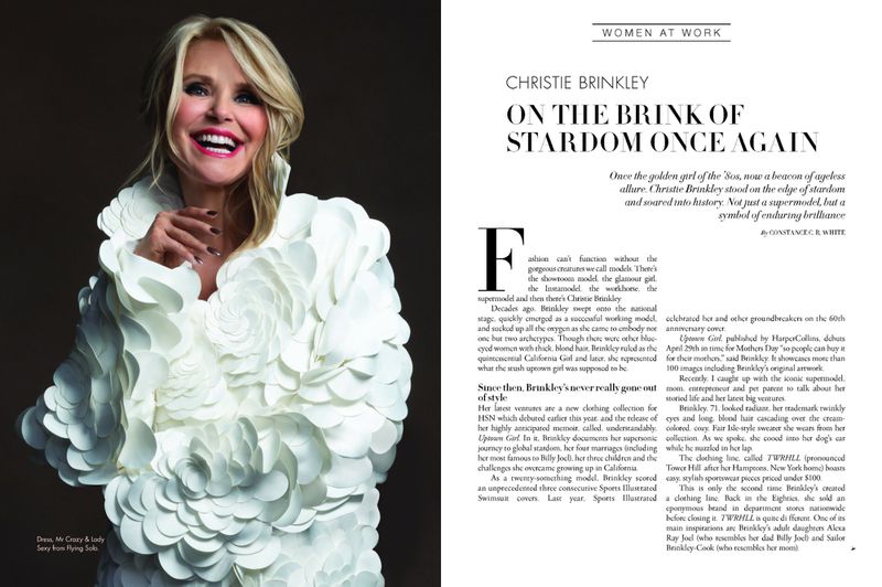 Blonde woman, Christie Brinkley, smiles wearing a white flower-petal dress in a magazine editorial. Makeup and hair styling complete the look.