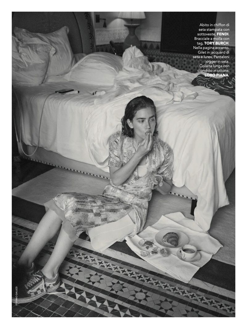 Model seated on tiled floor in patterned dress eating breakfast next to a bed for Marie Claire Italia