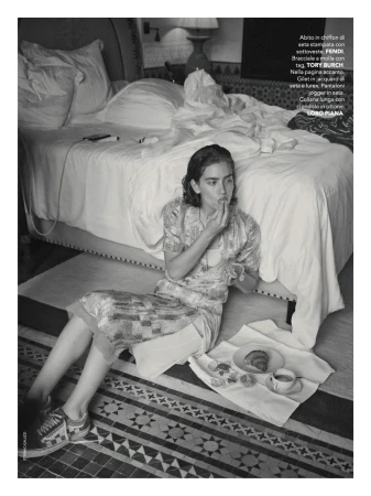 Model seated on tiled floor in patterned dress eating breakfast next to a bed for Marie Claire Italia
