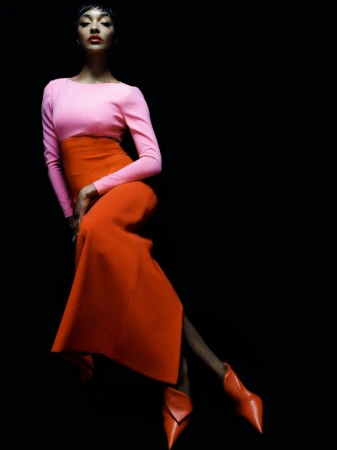 Model Jourdan Dunn wearing a pink top and orange skirt against a solid black background for Harper's Bazaar España