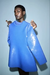 Model Fatou Kebbeh holding up a textured royal blue top in a studio portrait by Bibi Cornejo Borthwick for Beyond Noise.