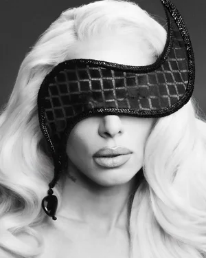 Close-up portrait of Julia Fox in black and white with long blonde hair wearing a patterned black eye mask for Tush Magazine.