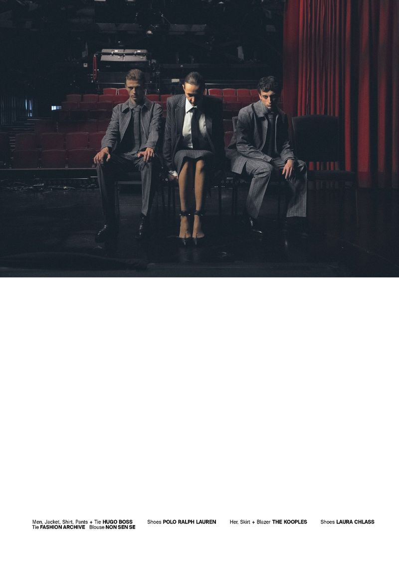 Three fashion models in suits pose seated on a stage with red curtains in the background, promoting HUGO BOSS, POLO RALPH LAUREN, THE KOOPLES, and LAURA CHIASE.